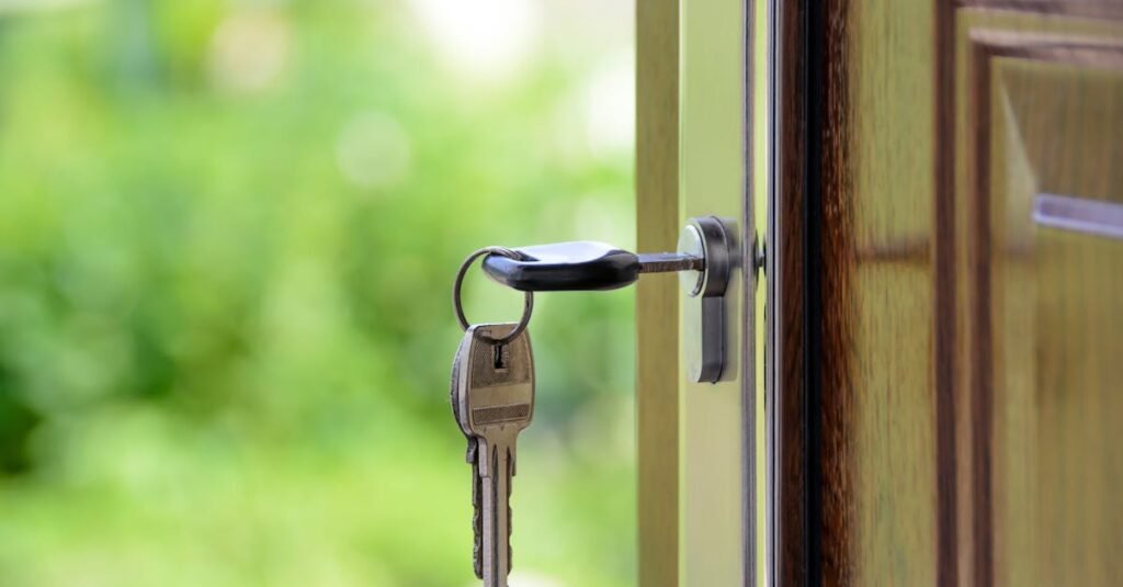 Key inserted in door lock against a blurred green background, symbolizing security and real estate.